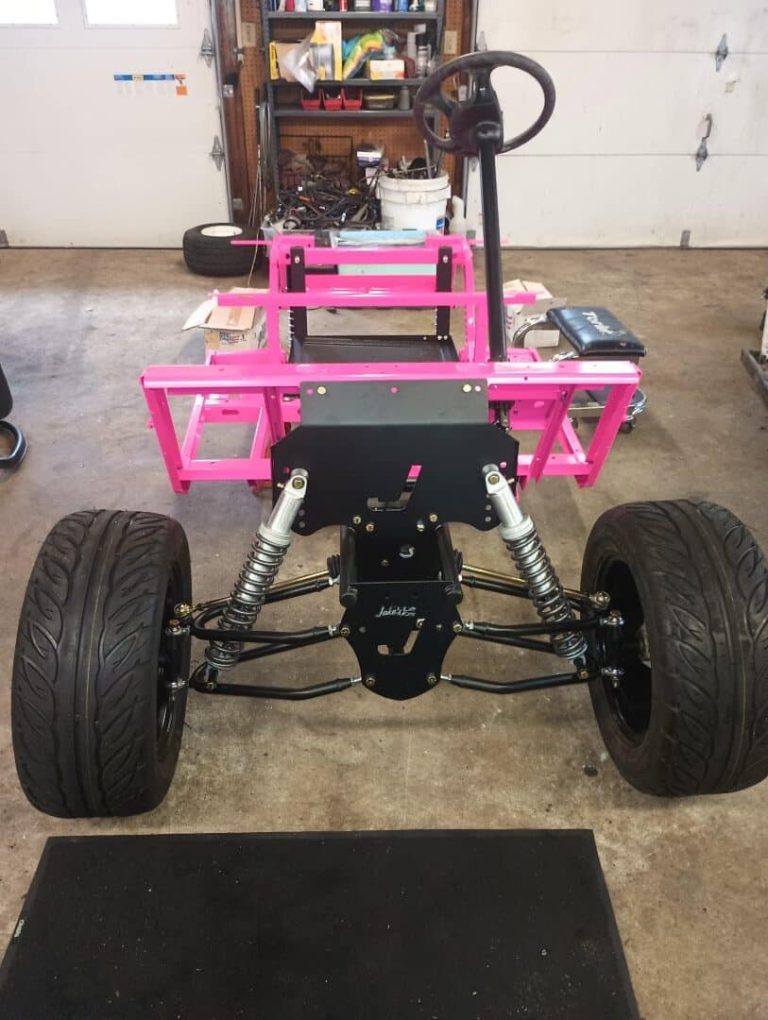 Custom golf cart frame with pink powder coating and suspension components.