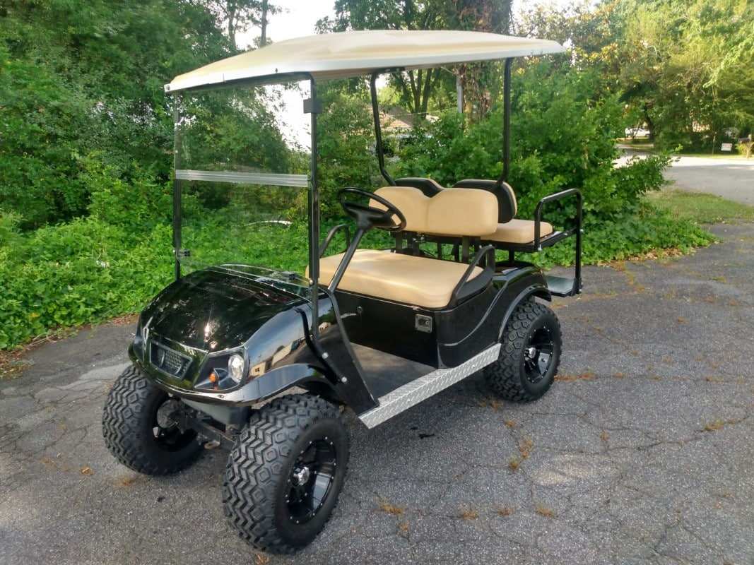 Customized black golf cart with tan seating and upgraded wheels